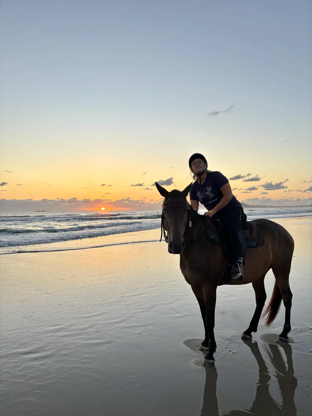 Horse and rider in the shallows at sunrise